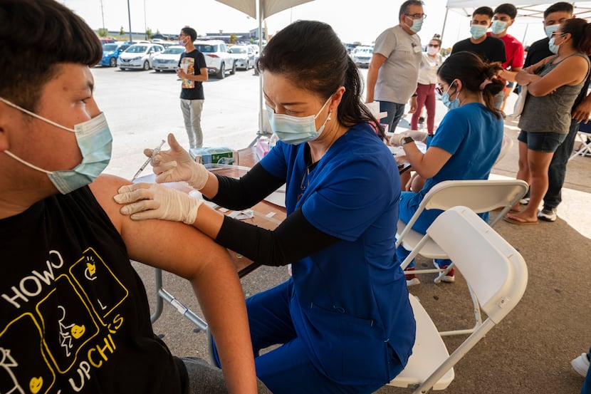Registered nurse Tammy Huynh administers a vaccine to Daniel Gurrola, 15, during a pop-up...