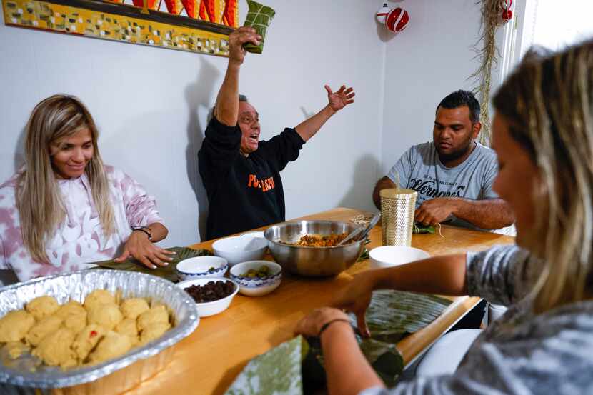 Luis Chacin, center, cheers after wrapping his first banana leaf while other family members...