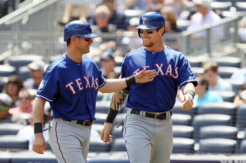 Josh Hamilton and Michael Young of the Texas Rangers celebrate after scoring in the first...