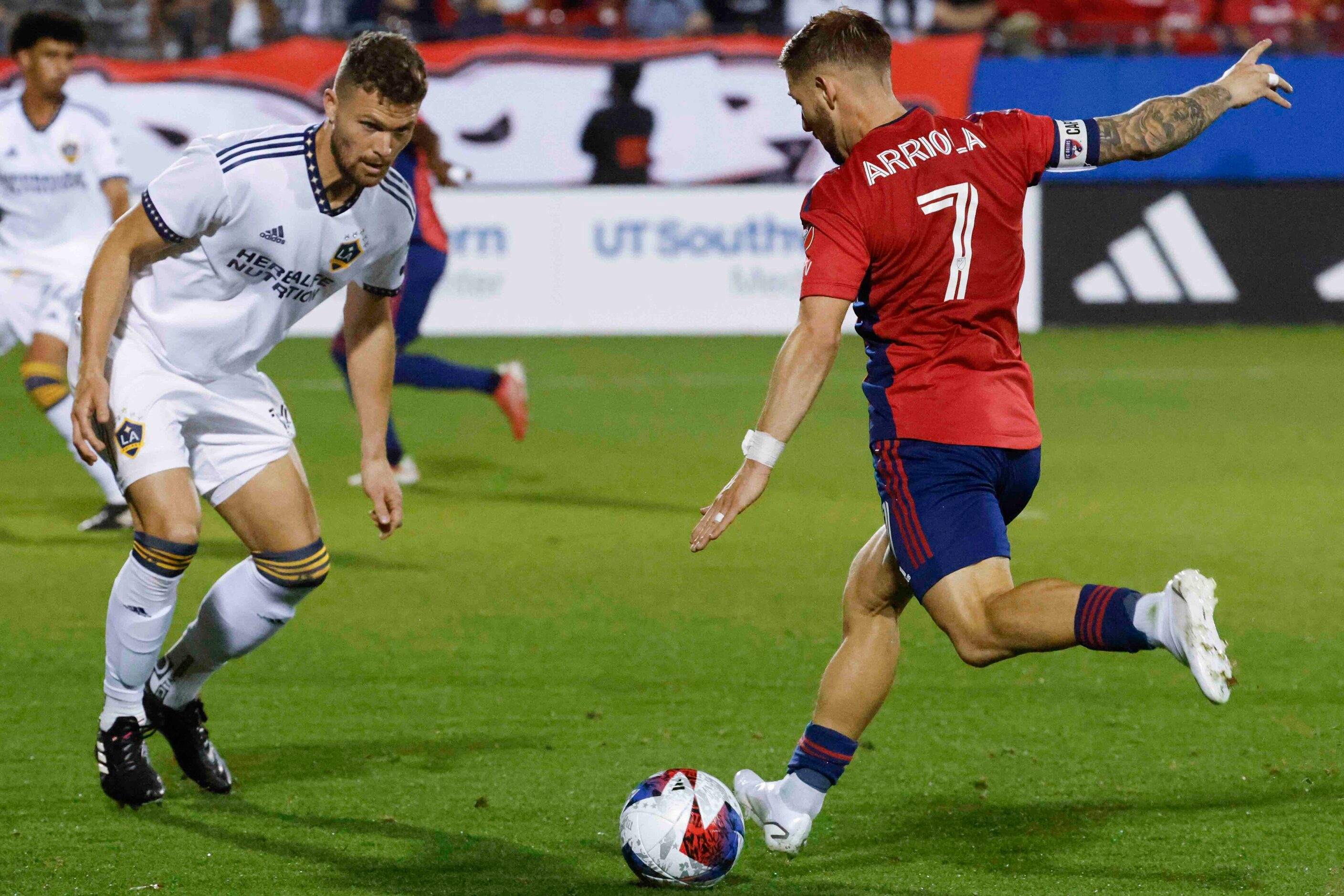 Los Angeles Galaxy defender Eriq Zavaleta (left) observes as FC Dallas forward Paul Arriola...