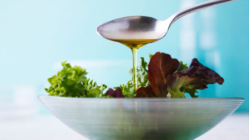 Pouring olive oil onto fresh salad