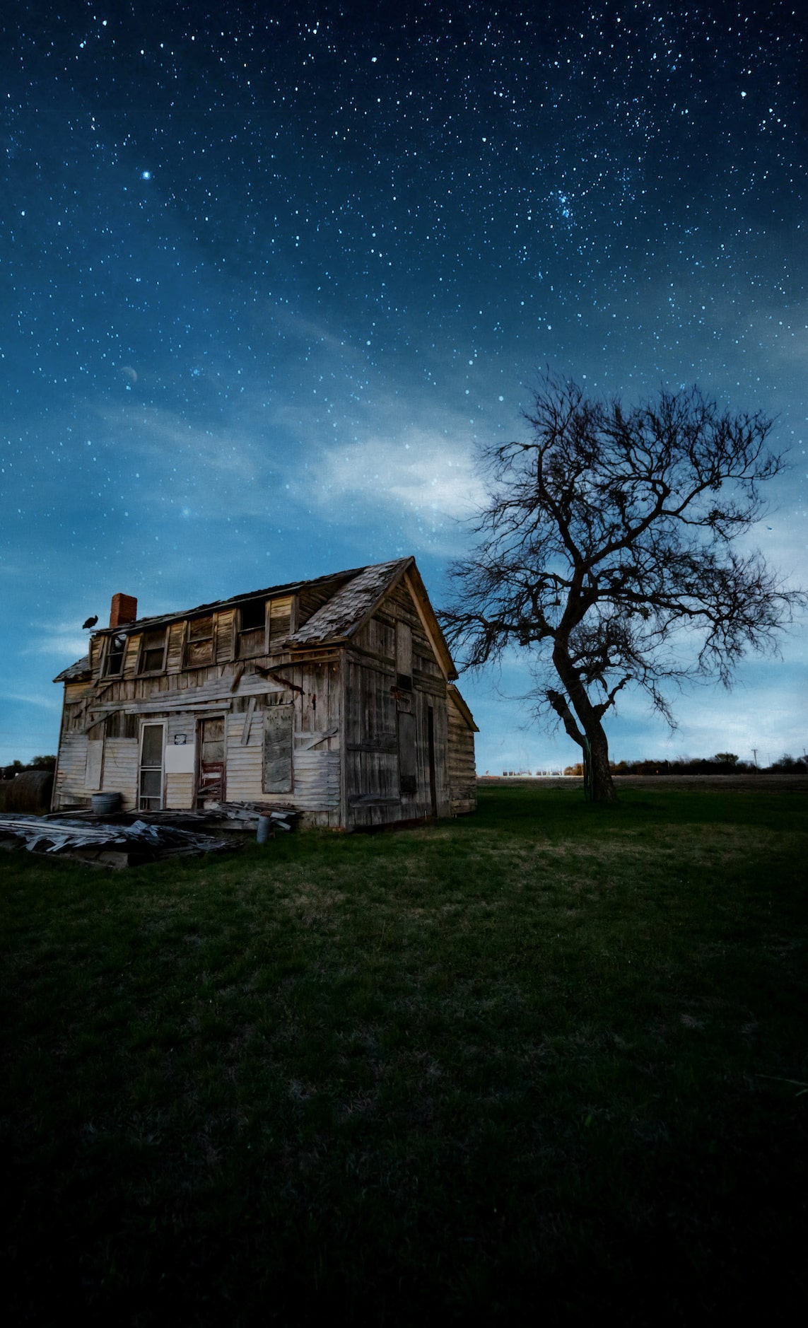 An abandoned farm house located outside of Dallas set against a starry night sky.