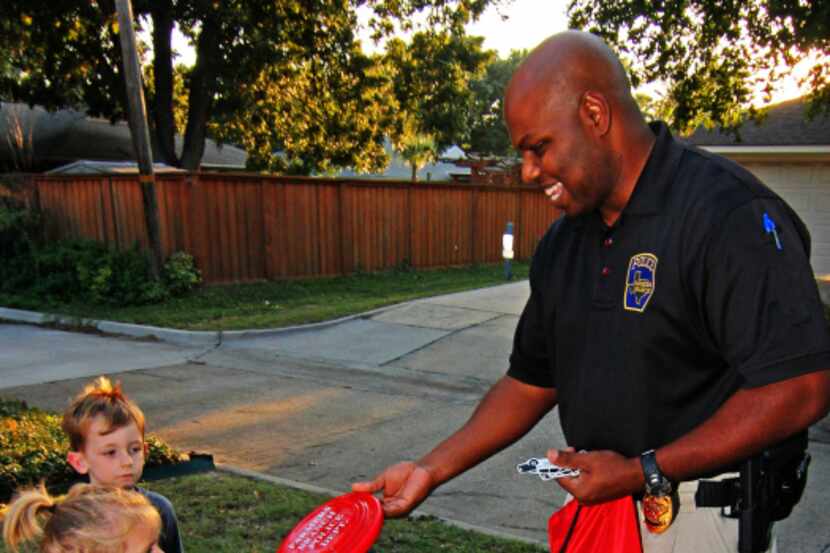 Sgt. Erik Stokes hands out a Frisbee to kids on Austell Parkway in Farmers Branch during the...