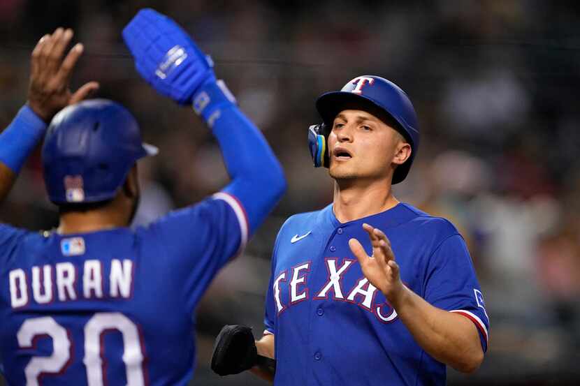 Texas Rangers' Corey Seager high fives Ezequiel Duran after they scored on a hit by...