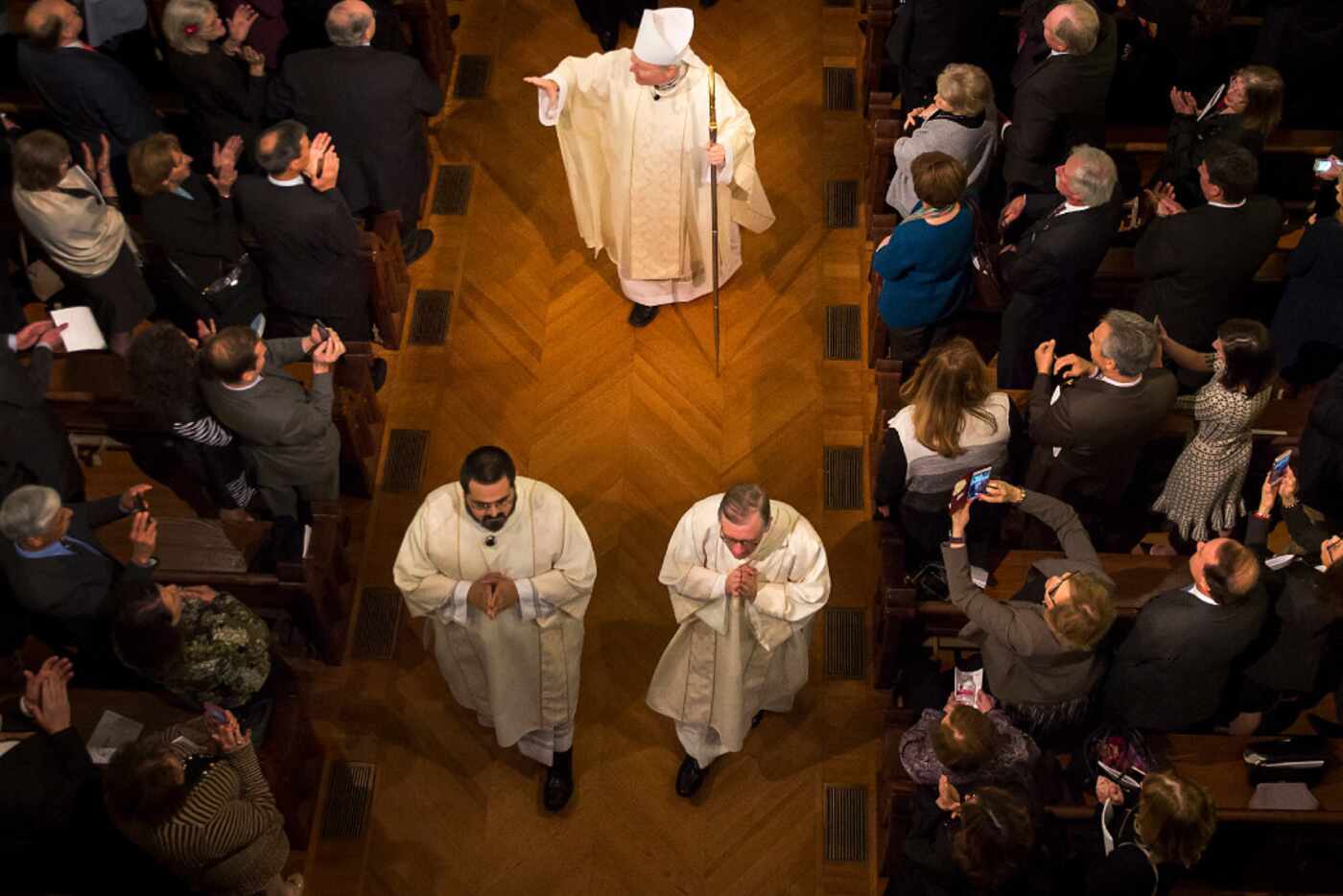 Bishop Edward J. Burns acknowledges the applause of worshipers as he processes from the...