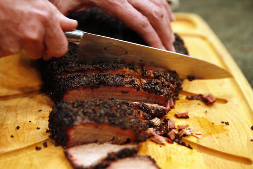 Todd David of Cattleack Barbecue cuts the smoked brisket in Mark Vamos' home in Dallas on...