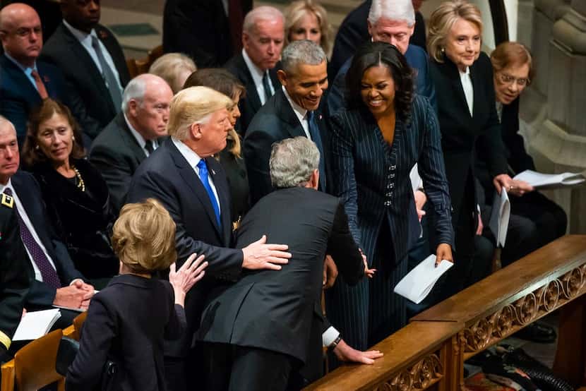 Former President George W. Bush hands candy to a laughing Michelle Obama as (from left)...