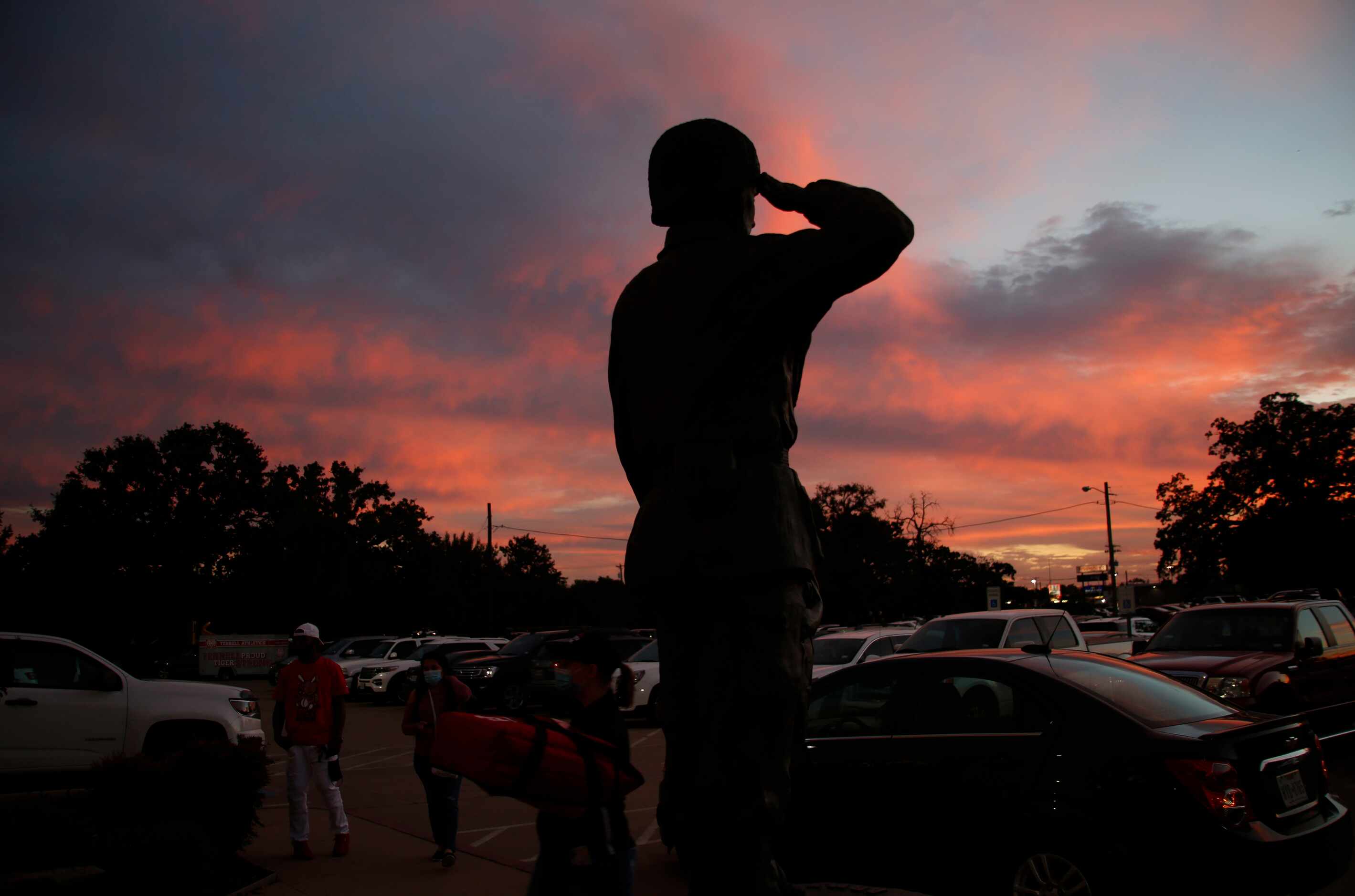 The statue of a combat soldier salutes arriving Terrell Tigers football fans at sunset prior...