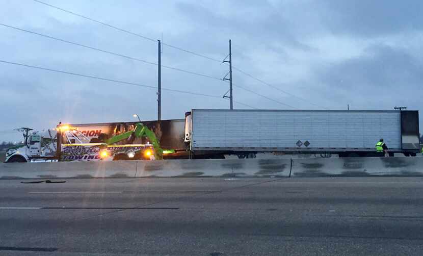  A wrecker moves into position to remove one of three 18-wheelers involved in a crash early...