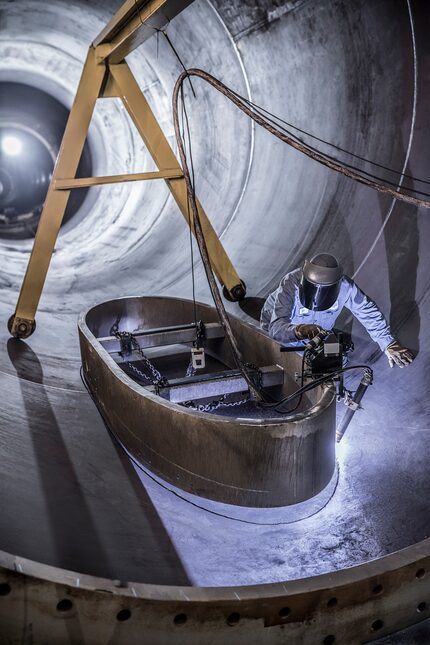 An Arcosa employee welding a wind tower door.