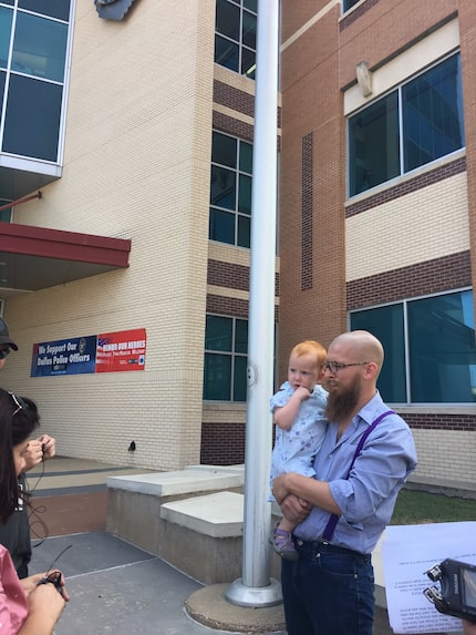 Anti-brutality activist holds his 2-year-old daughter while he speaks at a Friday news...