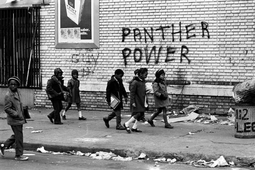 
Children walk past Black Panthers graffiti in a scene from The Black Panthers: Vanguard of...