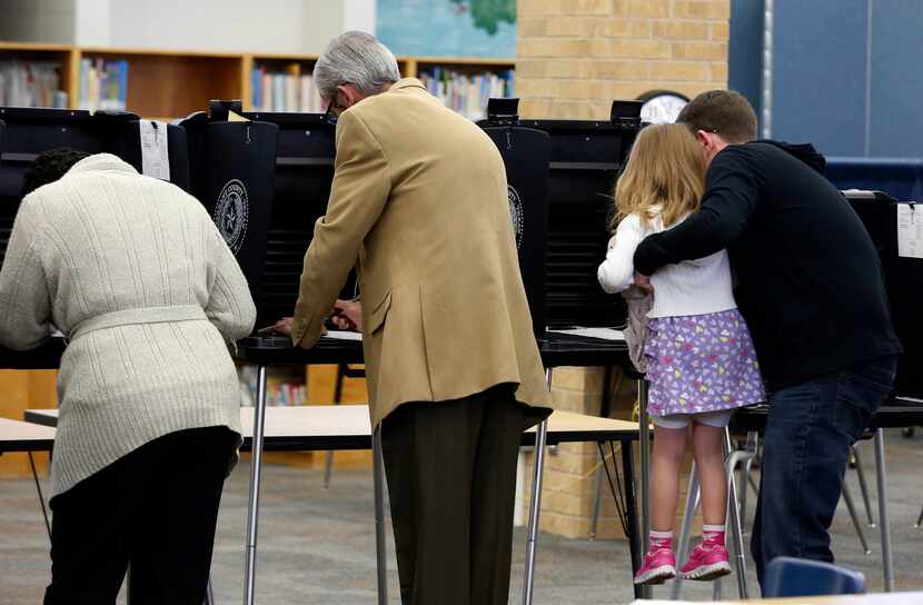 Joseph Nader lifts his daughter, 4-year-old Lydia Nader, to watch him cast his ballot...