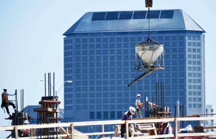 
Construction workers pour concrete at an apartment complex on Las Colinas Boulevard as the...