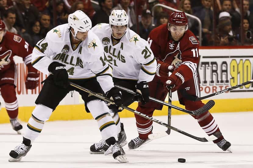 Dallas Stars' Jamie Benn (14) tries to keep the puck away from Phoenix Coyotes' Martin...