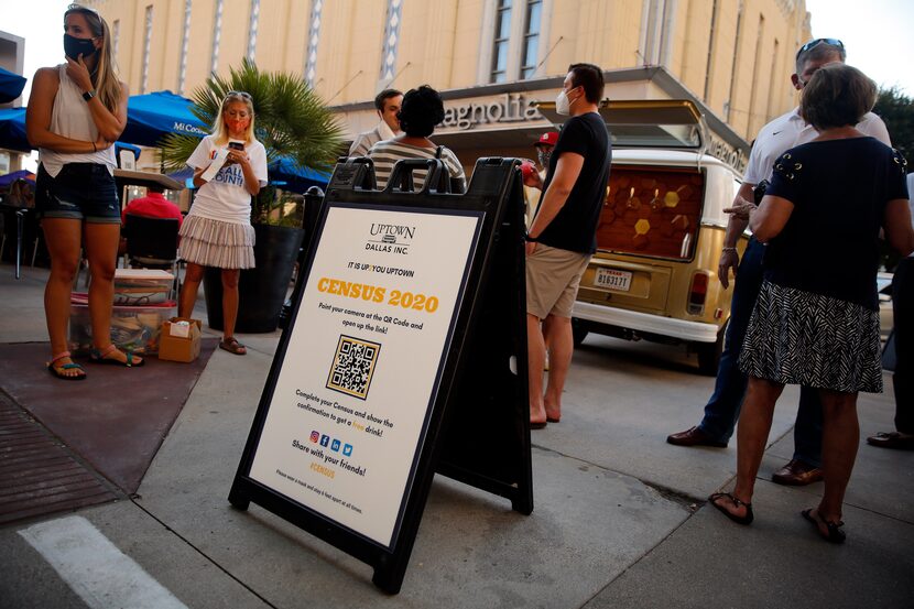 Volunteers with Uptown Dallas encourage people outside Mi Cocina at West Village shopping...