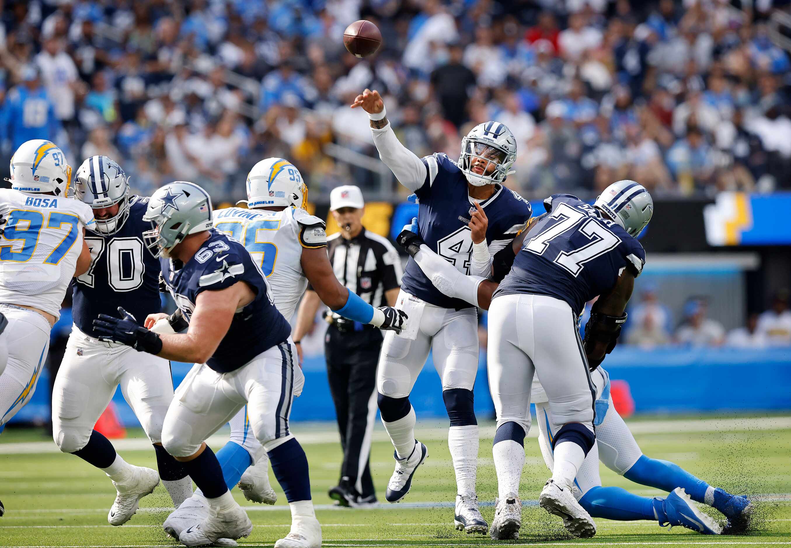 Dallas Cowboys quarterback Dak Prescott (4) throws from the pocket as he's grasped by a Los...