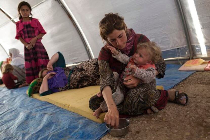 
An Iraqi Yazidi woman who fled her home in Sinjar feeds her child at Bajid Kandal refugee...