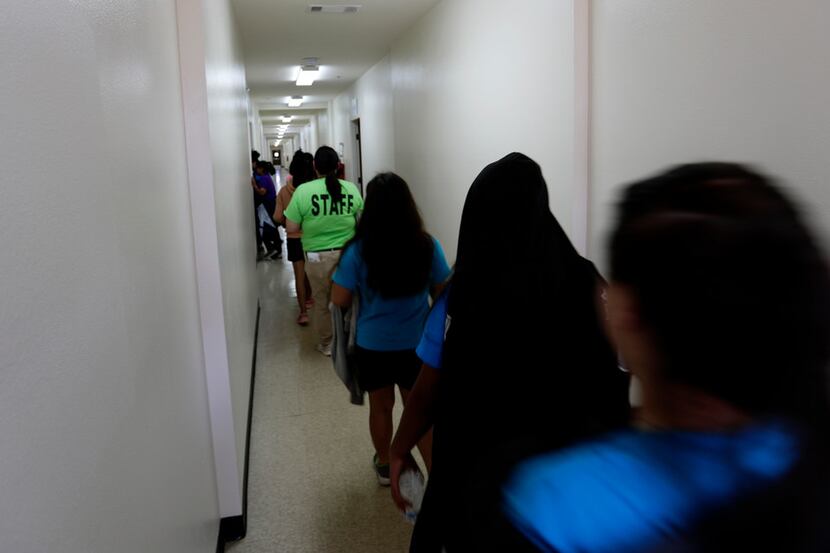 Immigrants walk down the hall of a dormitory at the U.S. government's newest holding center...