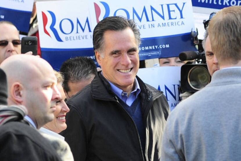 Republican presidential hopeful Mitt Romney greets supporters outside a polling station at...
