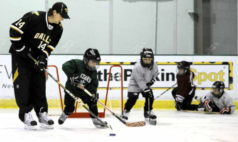 Dallas Stars left winger Jamie Benn goes through a drill with youth hockey players Saturday,...