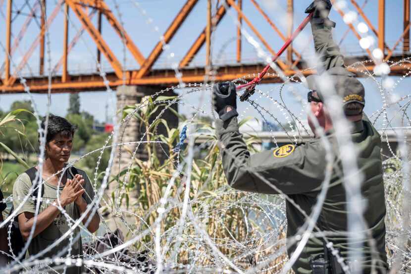 Un migrante de Venezuela agradece mientras un agente de la Patrulla Fronteriza corta el...