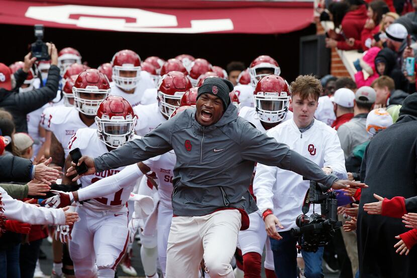 Former Oklahoma player Adrian Peterson leads the white team onto the field as an honorary...