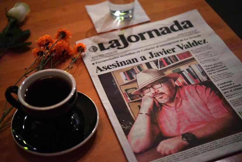 A makeshift altar with a cup of coffee and a newspaper headlining the story of slain Mexican...