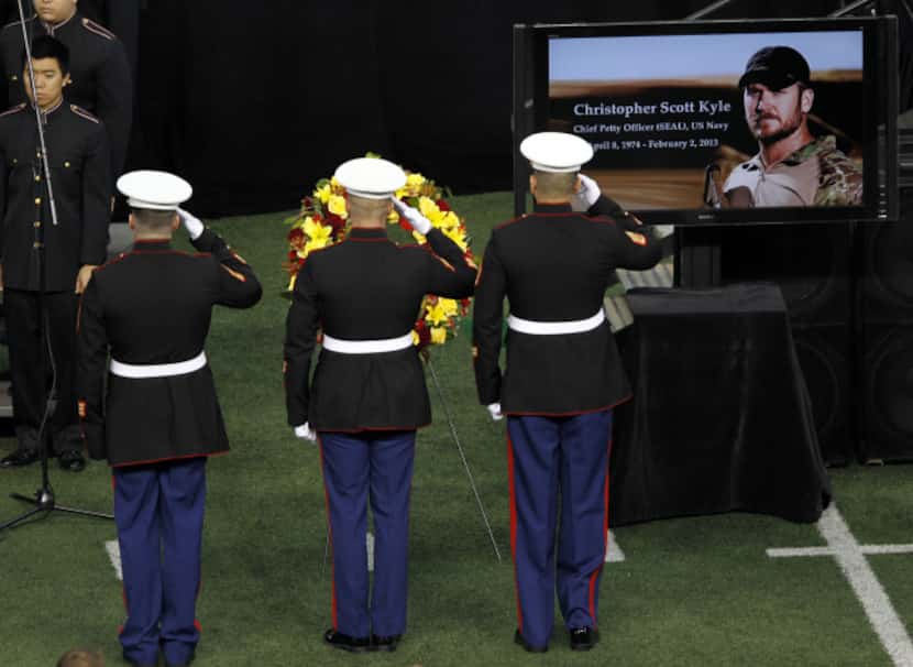 Members of the military salute after placing a wreath near the casket during a memorial...