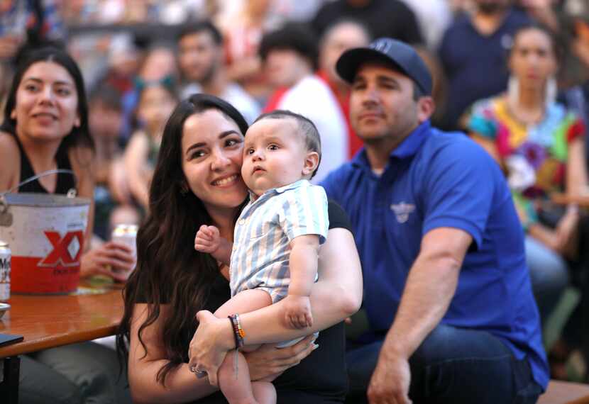 Eugene De La Garza and 6-month-old Ruben watch Rosas Divinas play at Legacy Hall.