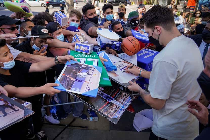 Dallas Mavericks guard Luka Doncic signs autographs for fans as he leaves the team hotel...