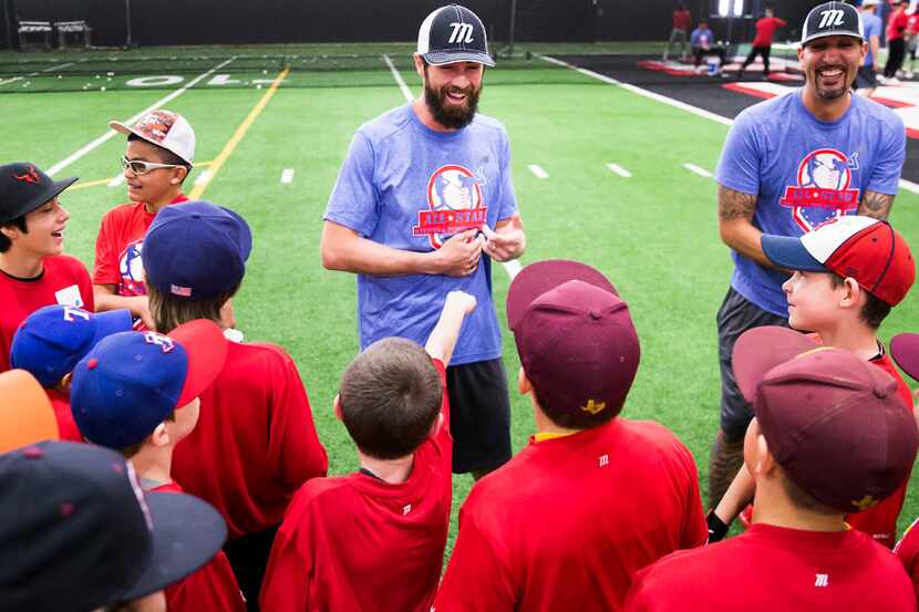 Texas Rangers pitcher Cole Hamels laughs with youngsters during a hitting and pitching...