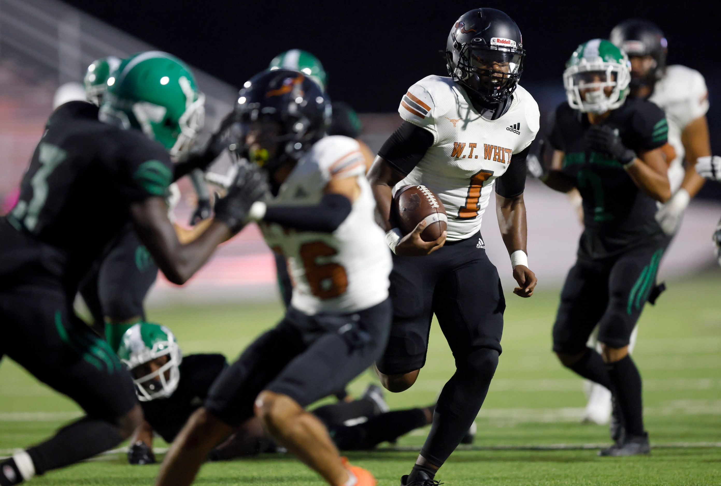 W.T. White quarterback Jaydyn Sisk (1) carries the ball as he’s pursued by the Bryan Adams...