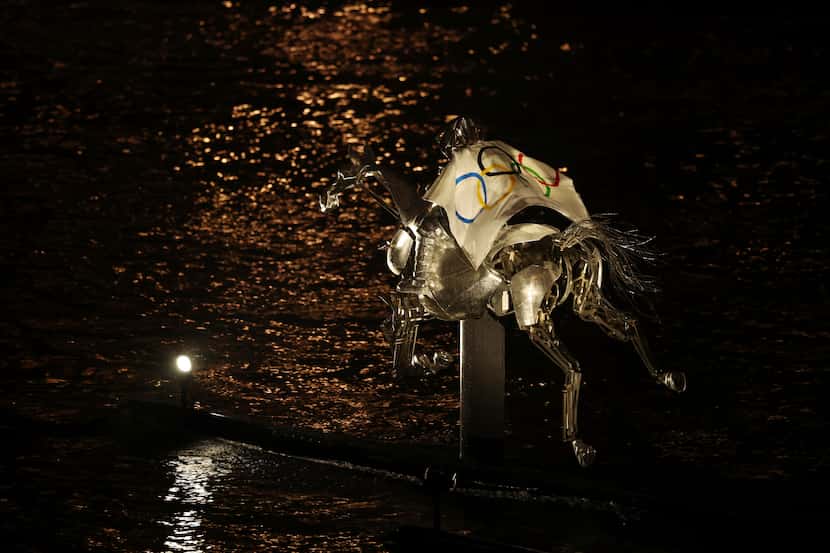 La amazona, envuelta en la bandera olímpica, cabalga por el río Sena durante la ceremonia de...