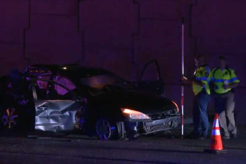 Fort Worth police examine a car involved in a wreck Tuesday morning on Interstate 35W. A...