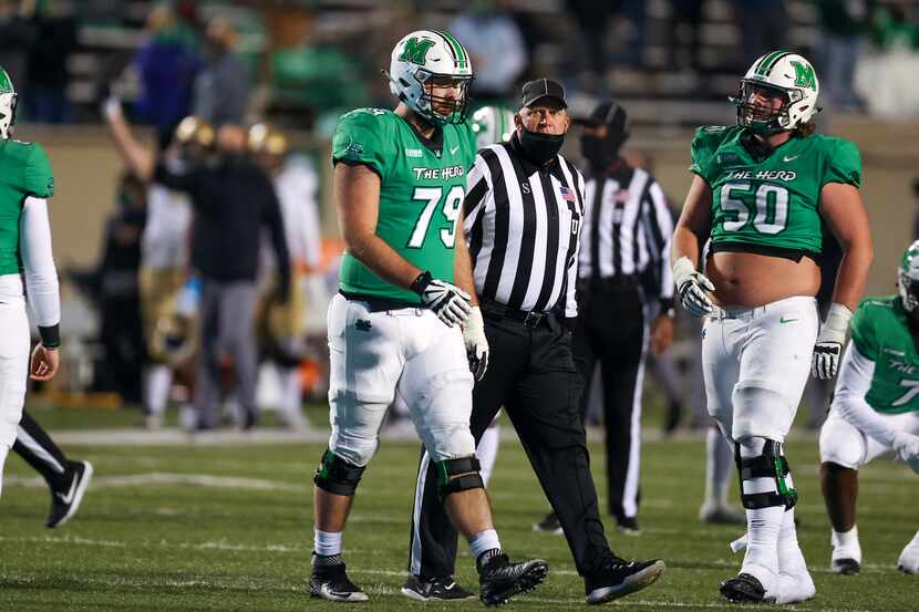 Marshall Thundering Herd offensive lineman Josh Ball (79) is escorted to the sideline by an...