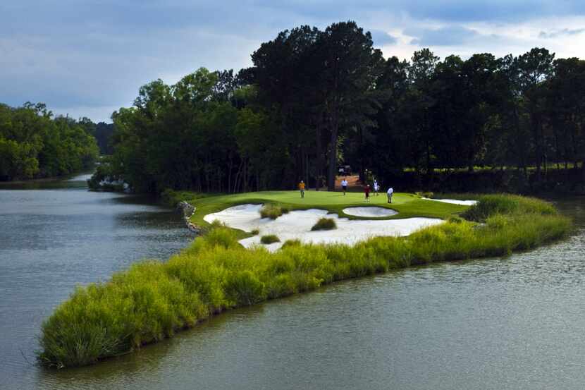 Golfers play the signature par 4, No. 15 green at Whispering Pines Golf Club in Trinity, TX,...
