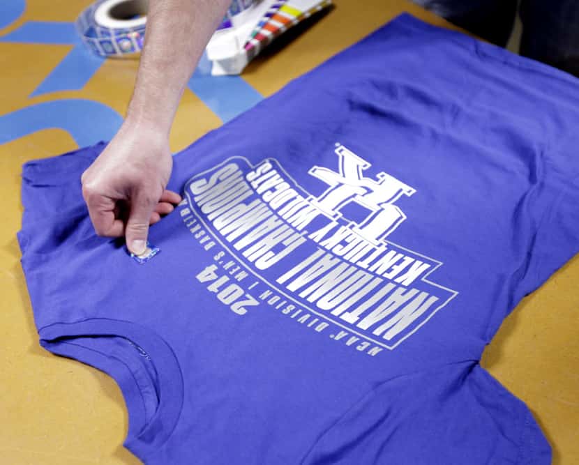 Scott Mitchell places a hologram sticker on an official NCAA championship t-shirt...