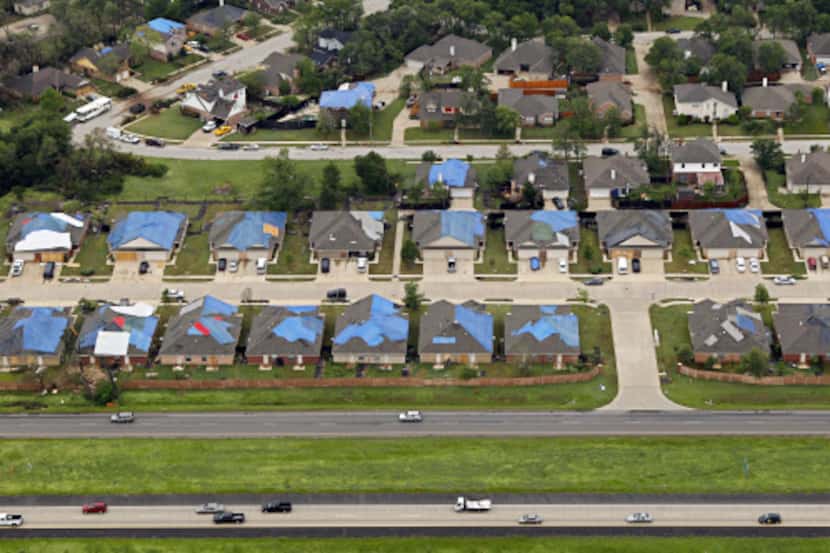 Tarps draped damaged roofs on homes in Kennedale Wednesday after a tornado ripped through...