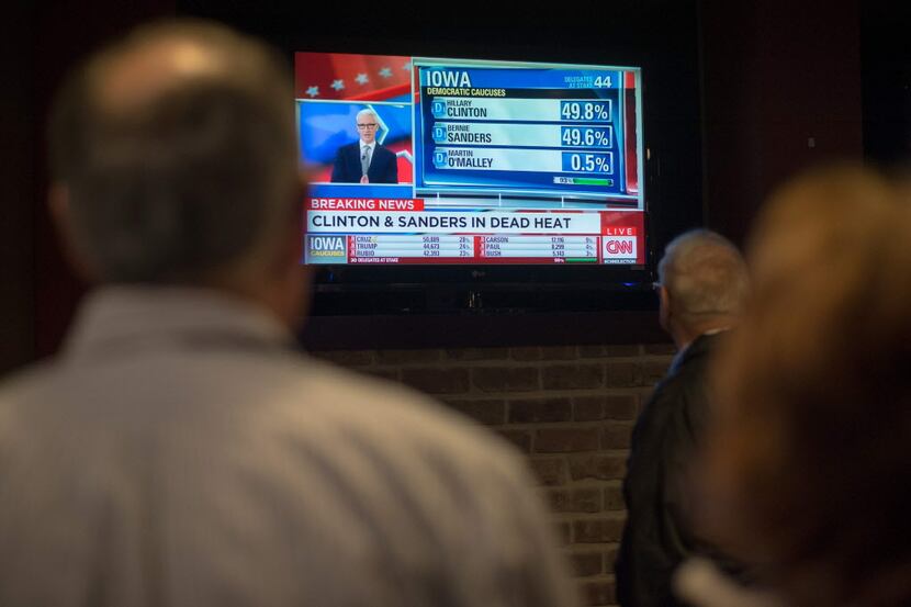  People look on as a television broadcast declares Senator Bernie Sanders and Hillary...