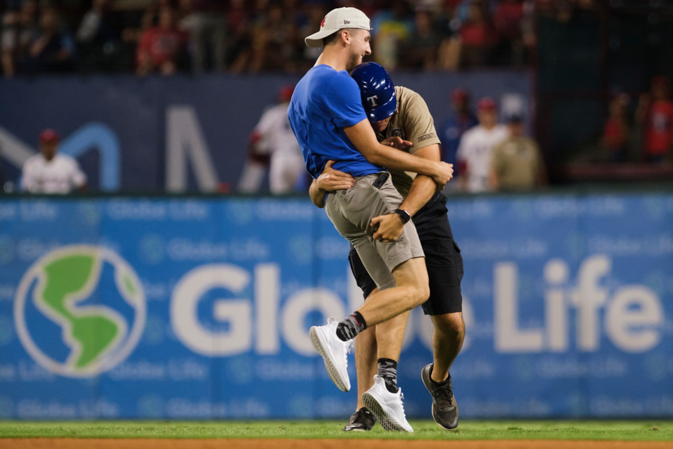 A security guard tackles a fan who ran on to the field during the ninth inning of a game...