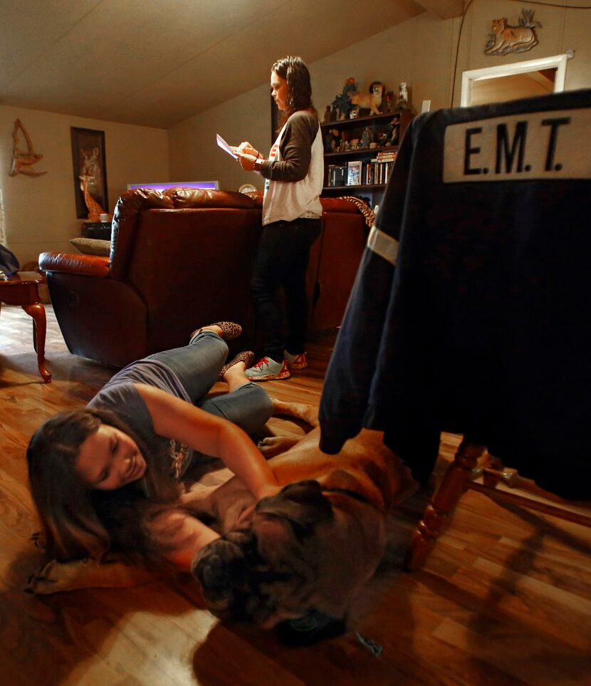 
Maleah Funk plays with their dog Maximus as her mother, Valorie Funk, goes over a checklist...