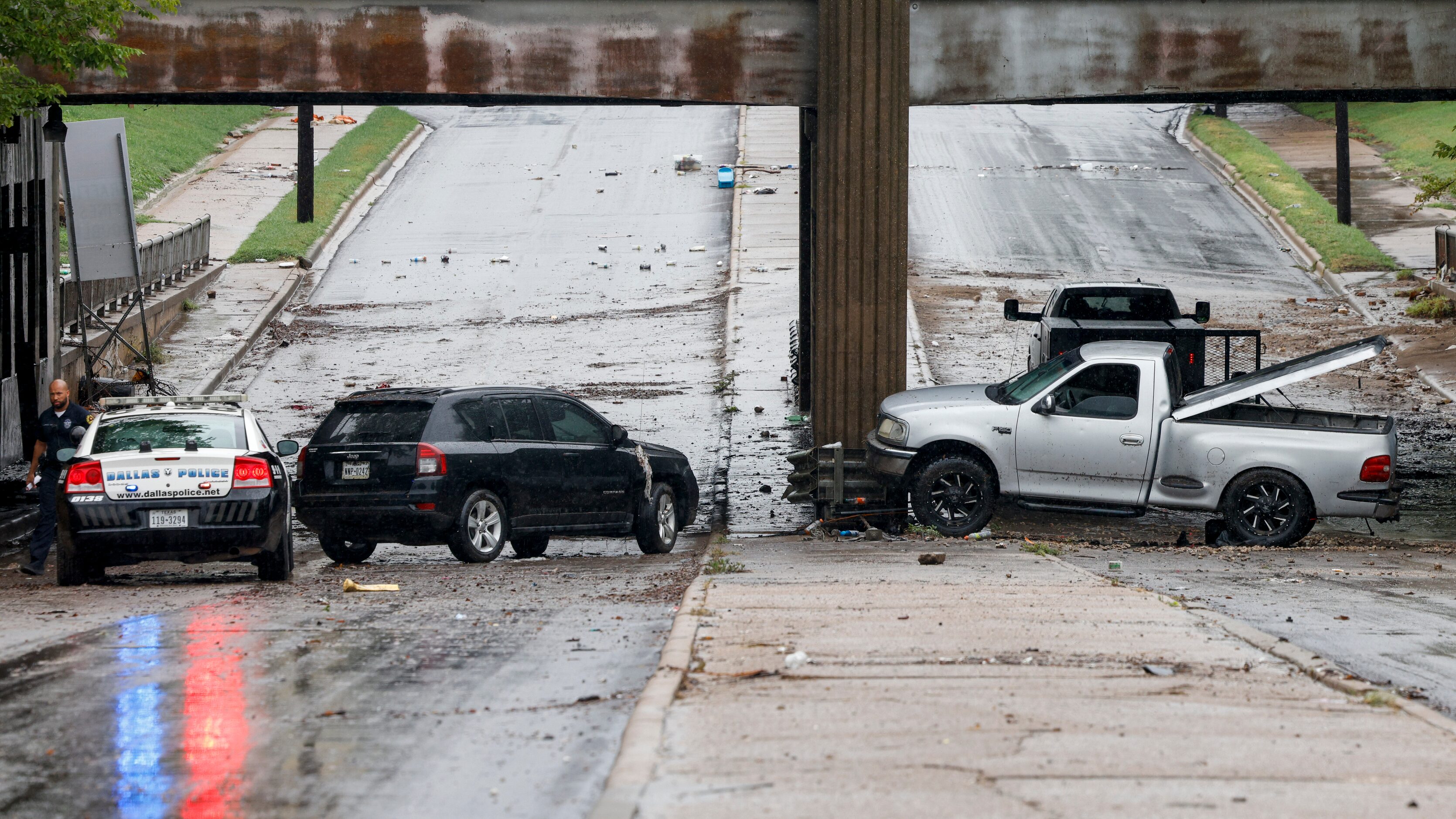 A Dallas police officer checks on two abandoned vehicles underneath an overpass along South...