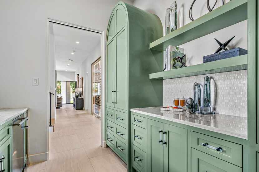 Green butler's pantry with storage space, light countertops and open shelves decorated with...
