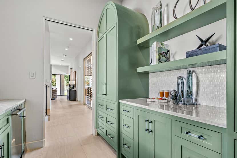 Green butler's pantry with storage space, light countertops and open shelves decorated with...