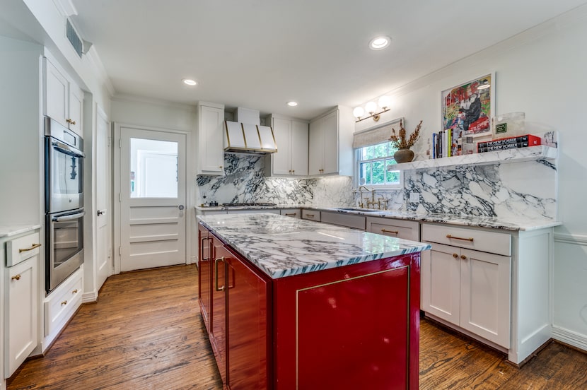 Kitchen with white cabinets, marble counters, lacquer red center island