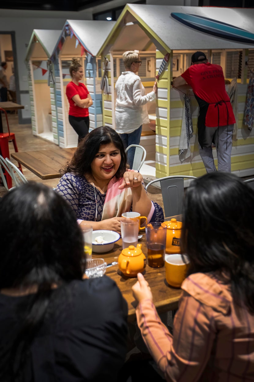 Rifat Malik (center) talks with friends as they meet at Fish & Fizz, a British restaurant,...