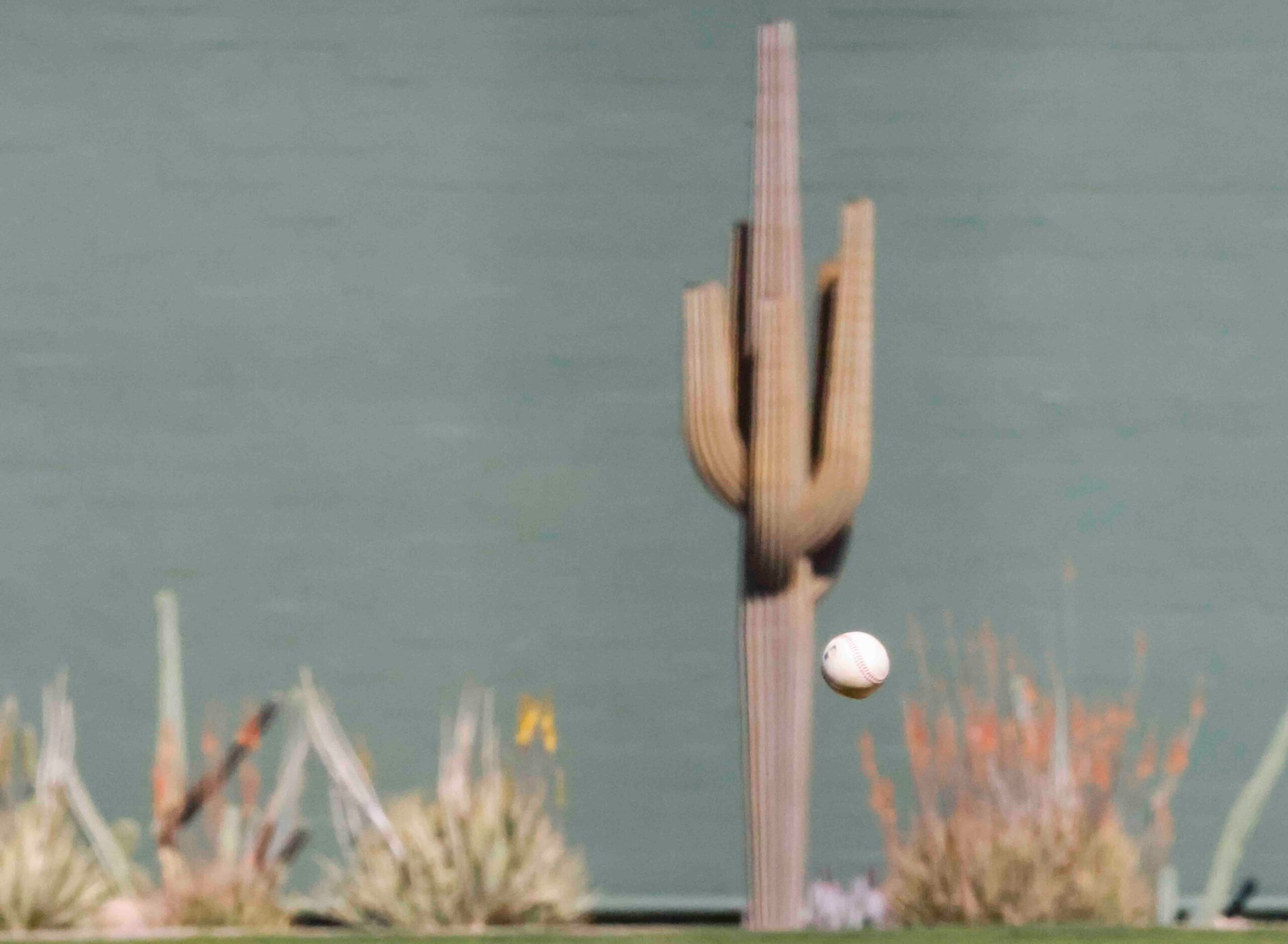 A baseball flies with a background of cactus during the fourth inning of a spring training...