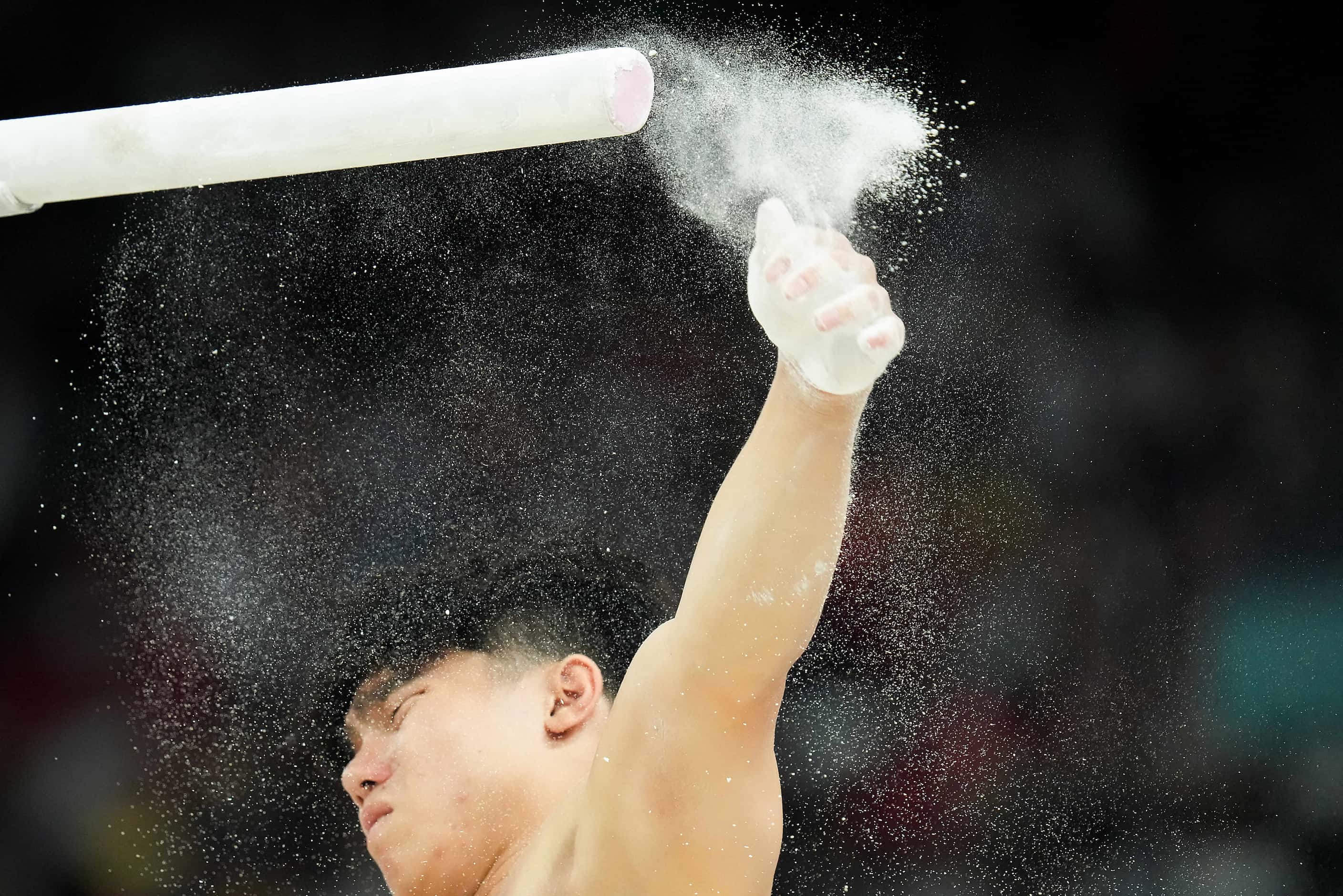 Chalk flies as Asher Hong of the United States prepares to compete on the parallel bars...