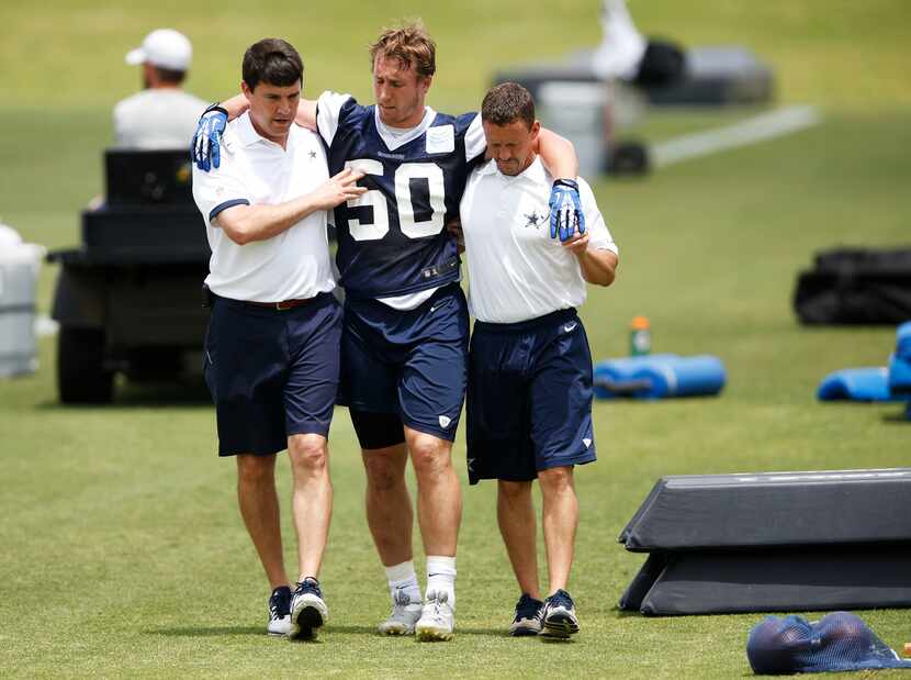 Dallas Cowboys Sean Lee is helped off the field by Dallas Cowboys head athletic trainer Jim...